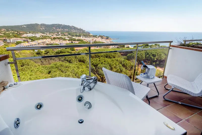Jacuzzi sur une terrasse avec vue sur la mer et les collines.