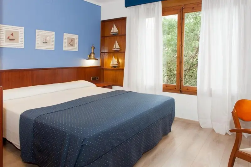 Une chambre lumineuse avec un lit recouvert d'une couverture bleue et des décorations maritimes.
