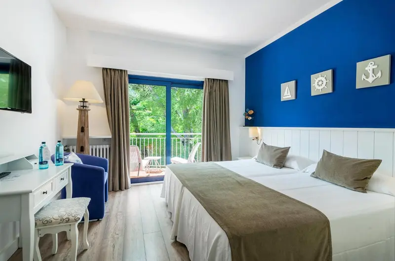 Une chambre lumineuse avec un lit double et un coin salon.
