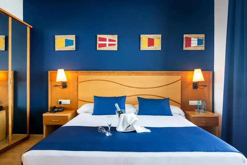 Une chambre avec un grand lit recouvert d'une courtepointe bleue et de coussins.