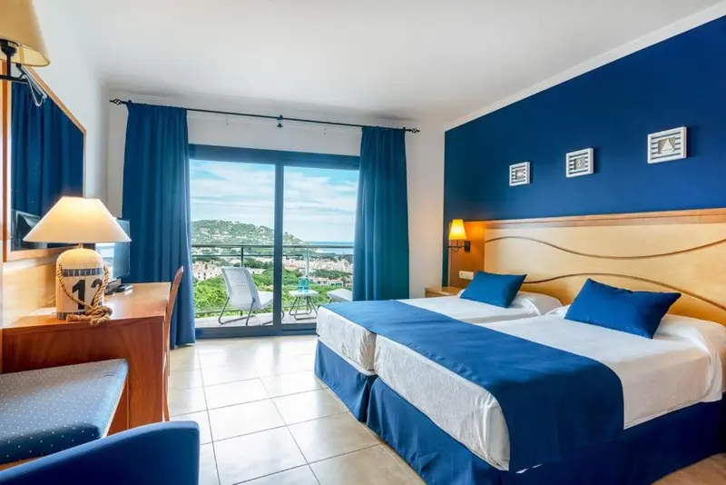 Chambre lumineuse avec un grand lit et vue sur la mer.