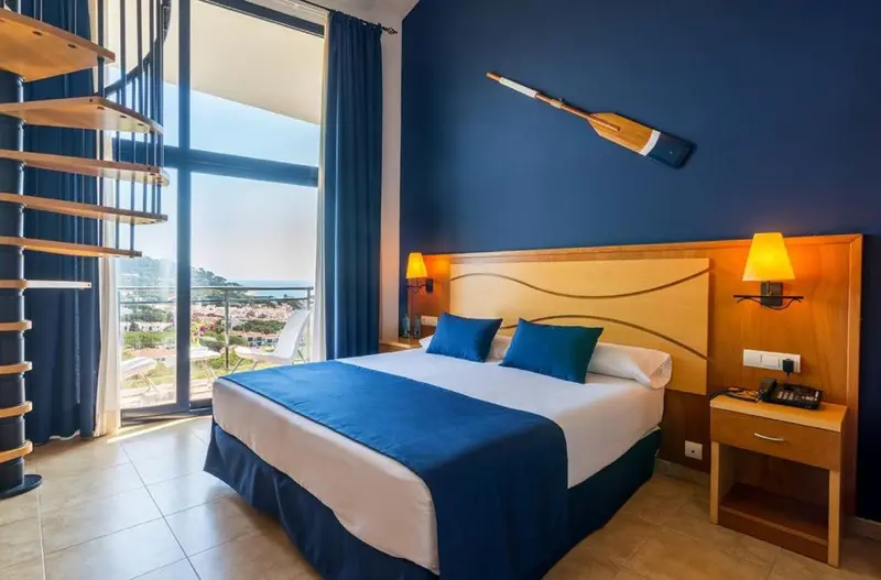 Chambre lumineuse avec un grand lit et vue sur la mer.