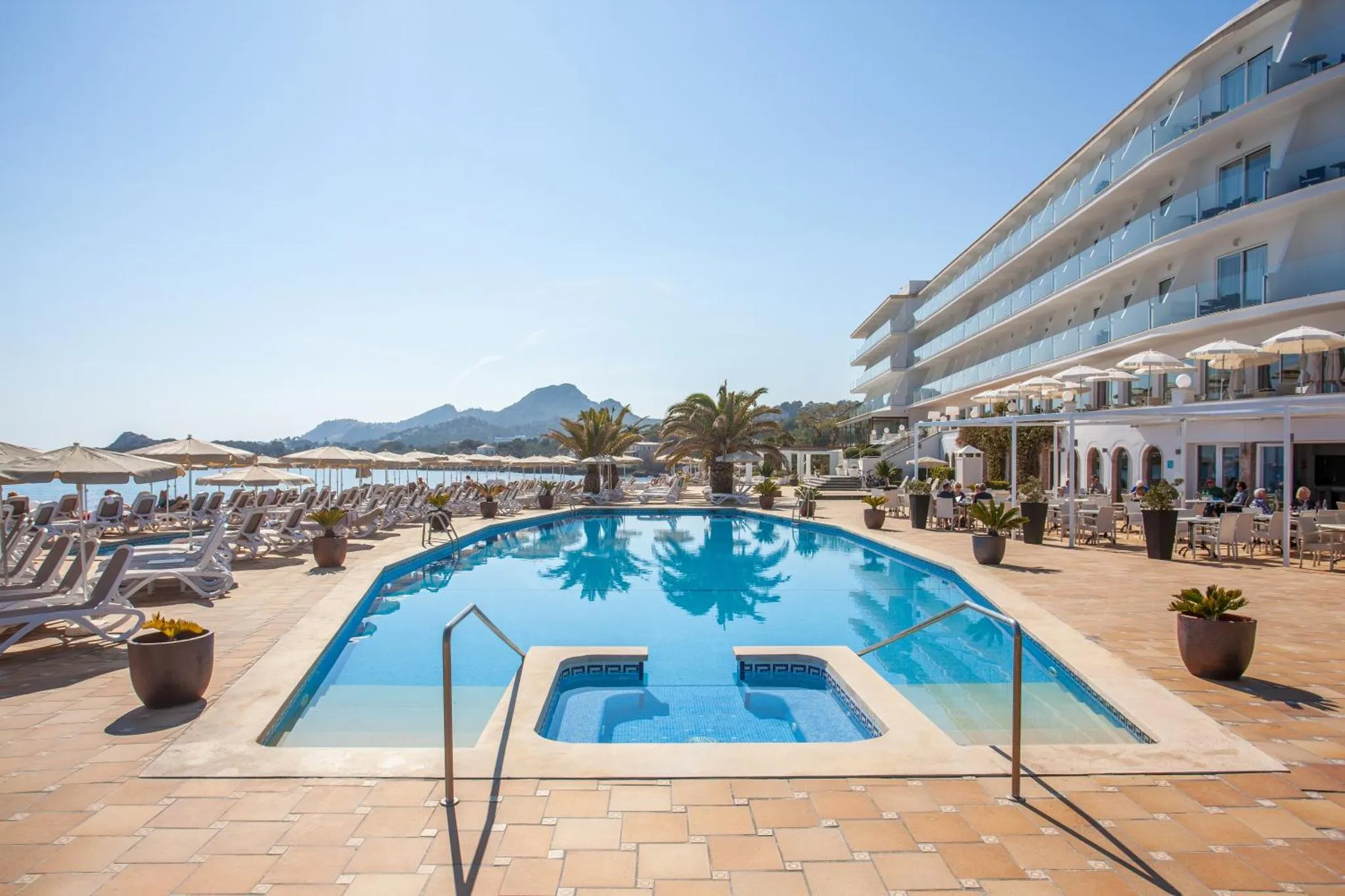 Une piscine rectangulaire avec des transats et des parasols en bord de mer.