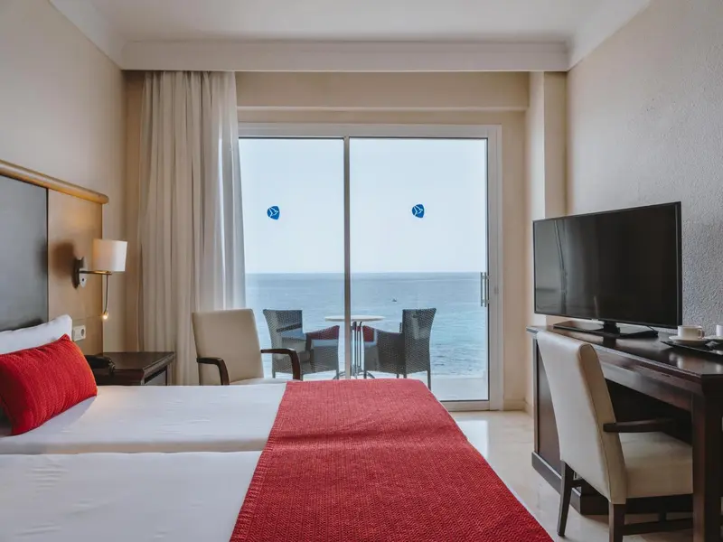 Chambre lumineuse avec un lit et une vue sur la mer.