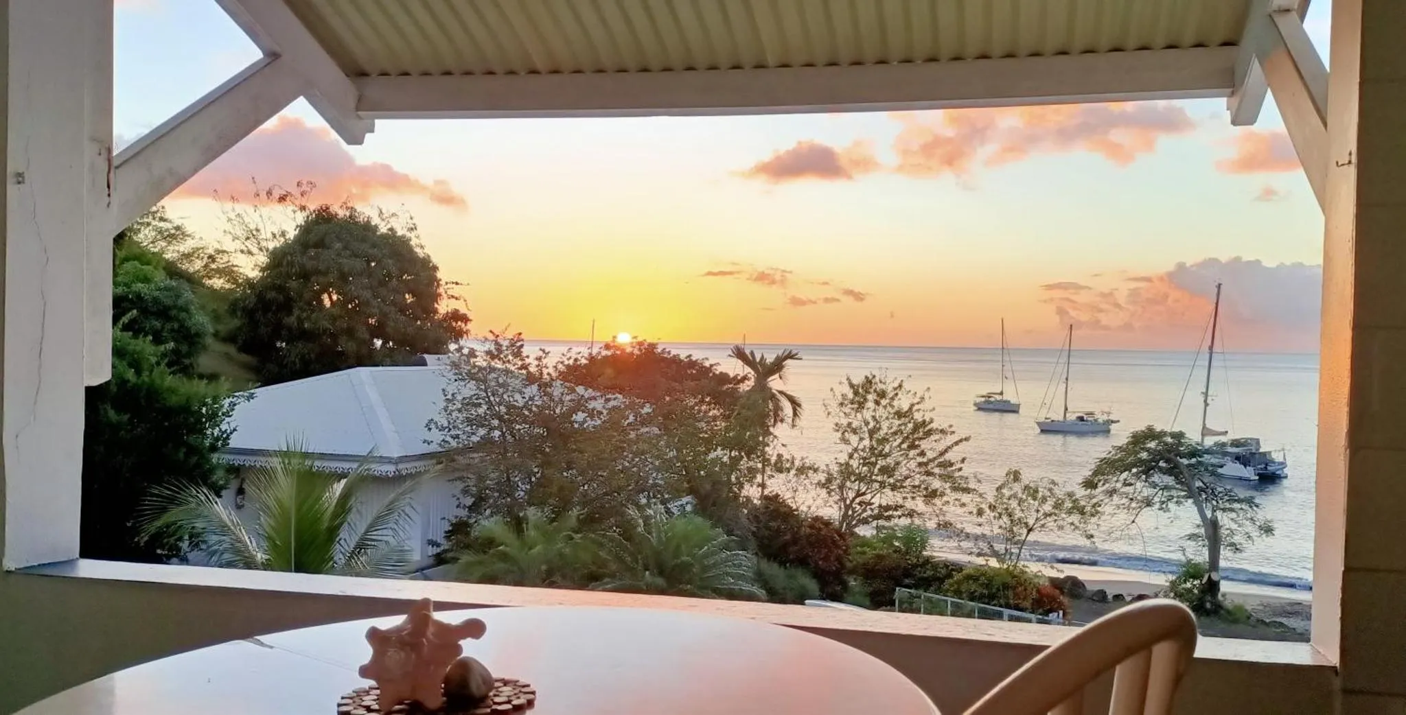 Vue sur la mer au coucher du soleil depuis une terrasse.