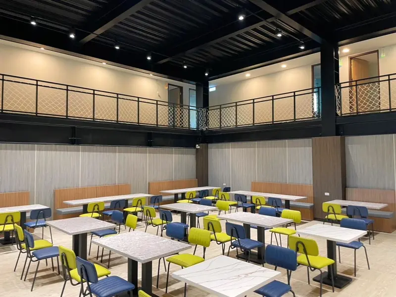 Une salle lumineuse avec des tables et des chaises disposées pour les repas.
