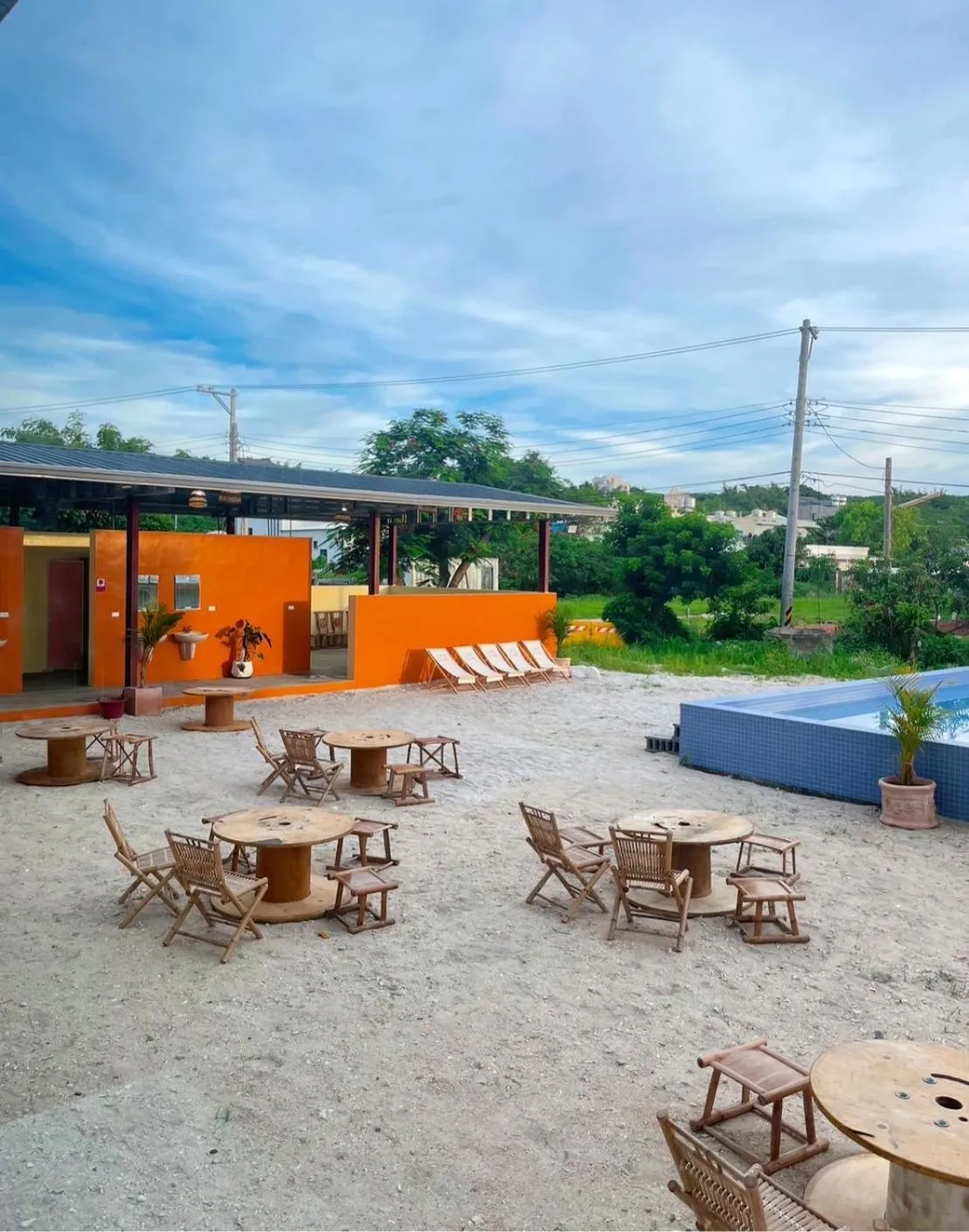 Terrasse ensoleillée avec tables et chaises près d'une piscine.