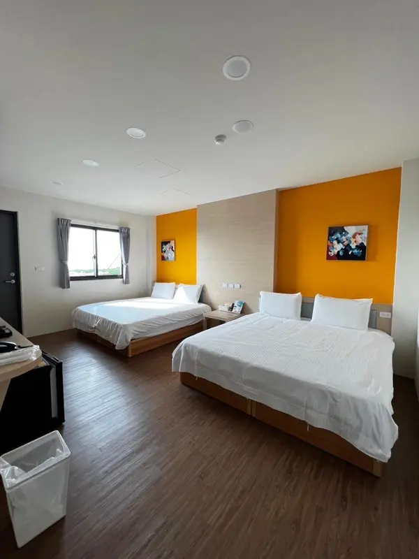 Chambre lumineuse avec deux lits simples et un mur orange.