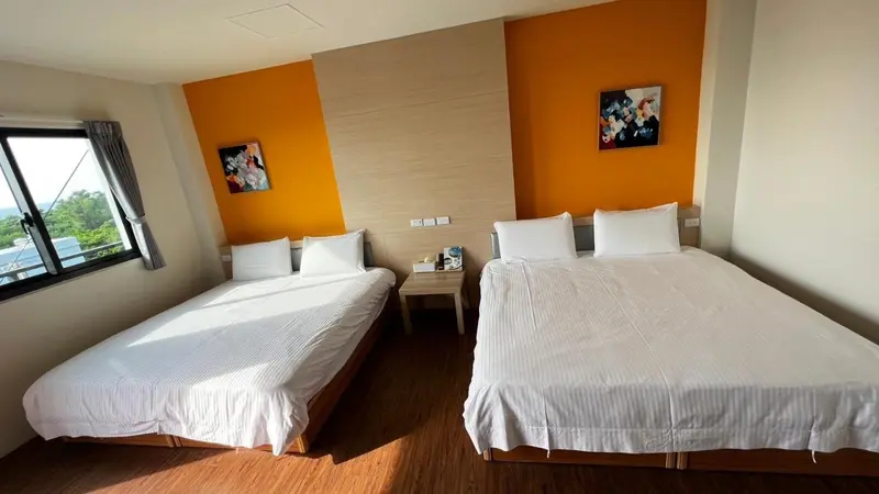 Une chambre lumineuse avec deux lits simples et une décoration murale colorée.