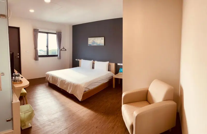 Une chambre lumineuse avec un lit double et un fauteuil.