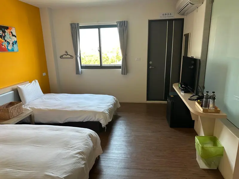 Une chambre lumineuse avec deux lits simples et un téléviseur.