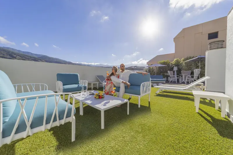Un couple se détend sur une terrasse aménagée avec des fauteuils et une table basse.
