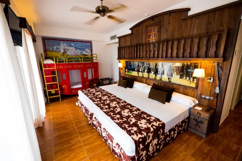 Une chambre avec un lit double et un lit superposé décoré sur le thème du Far West.