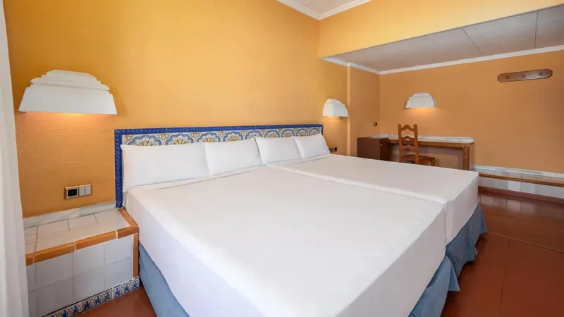 Une chambre lumineuse avec un grand lit recouvert de draps blancs.