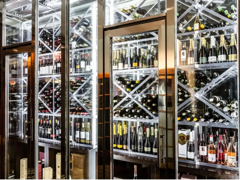 Cave à vin avec des étagères illuminées remplies de bouteilles.