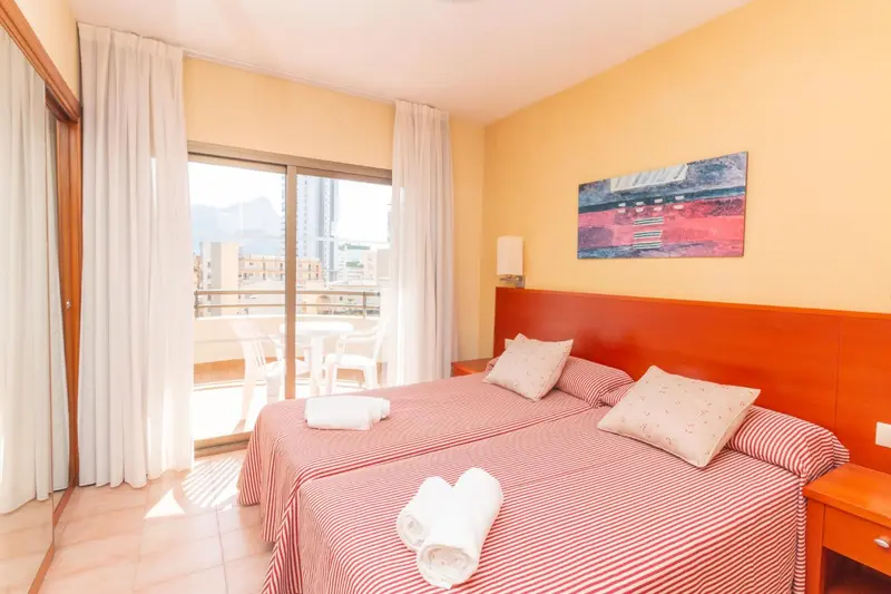 Une chambre lumineuse avec un lit double et un accès à un balcon.