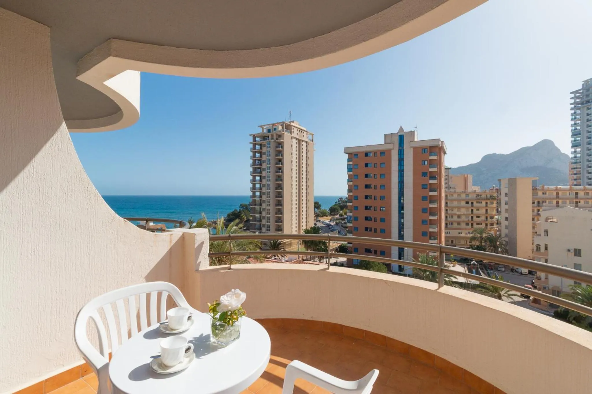 Une terrasse avec une table et des chaises offre une vue sur la mer et la ville.