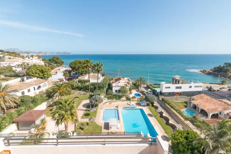 Vue aérienne d'une piscine et de bâtiments côtiers ensoleillés.