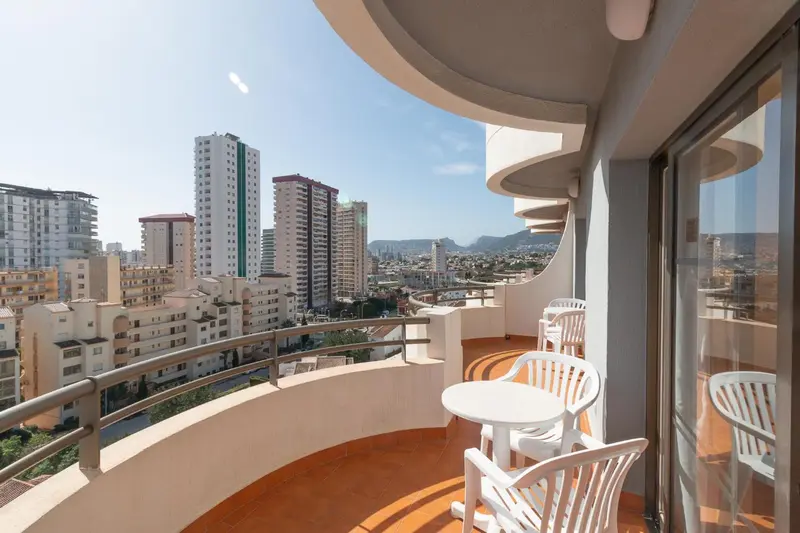 Terrasse avec mobilier blanc donnant sur une vue urbaine et la mer.