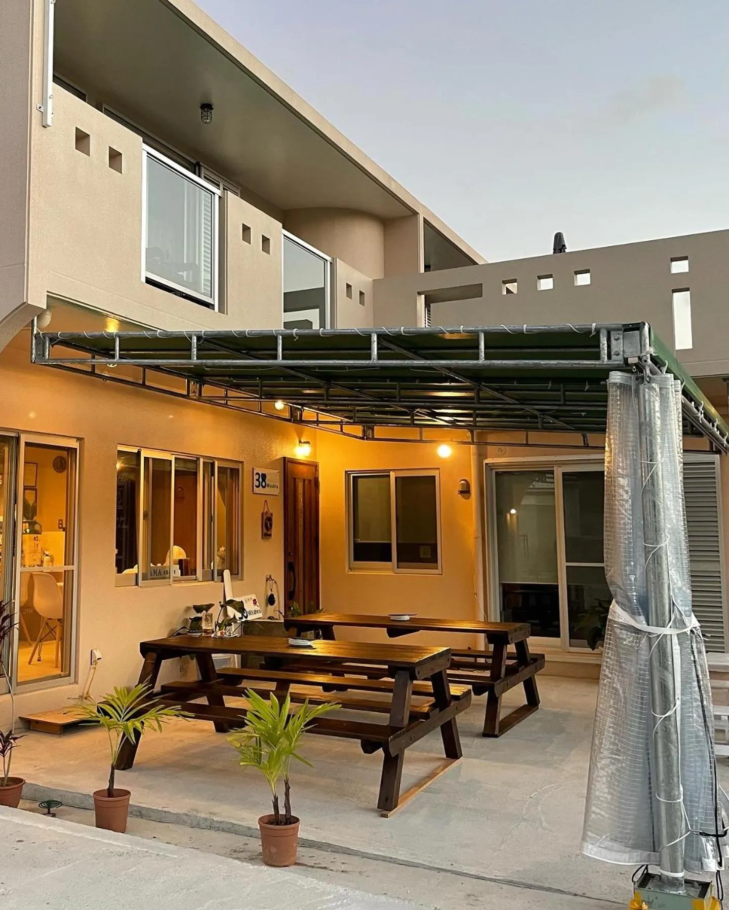 Terrasse ombragée avec tables et chaises en bois devant un bâtiment.