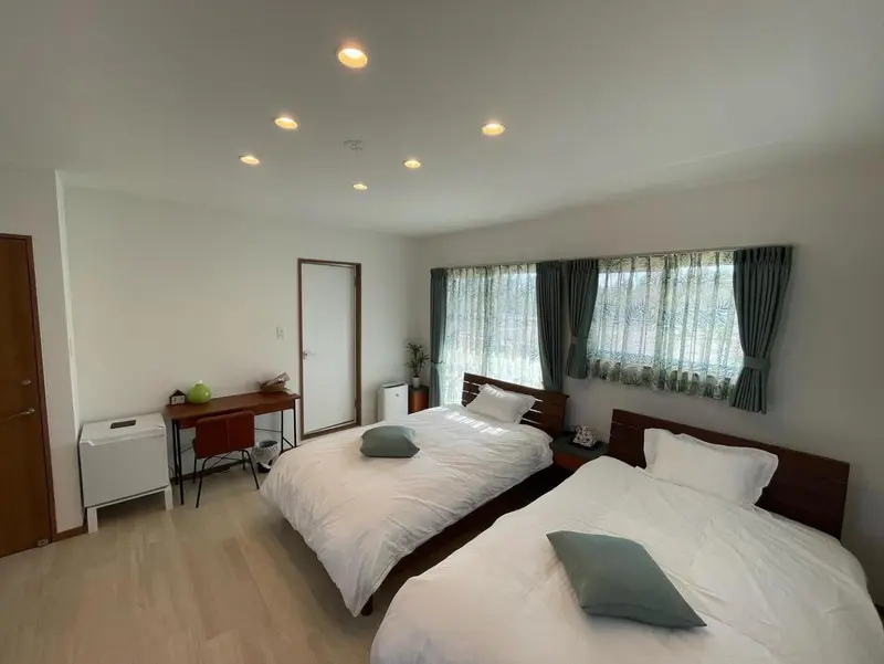 Une chambre lumineuse avec deux lits simples et un bureau.