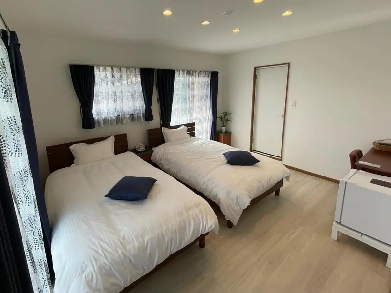 Une chambre lumineuse avec deux lits simples et des rideaux bleu marine.