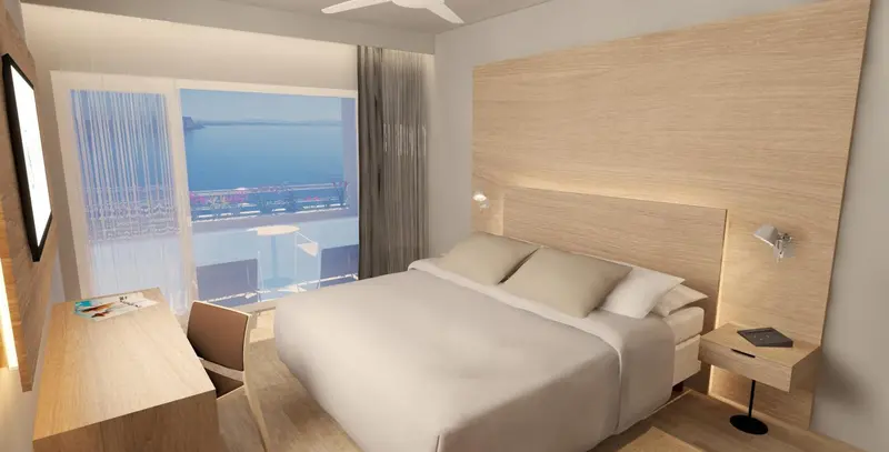 Chambre lumineuse avec un grand lit et vue sur la mer.