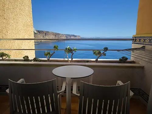 Terrasse avec table et chaises donnant sur la mer.