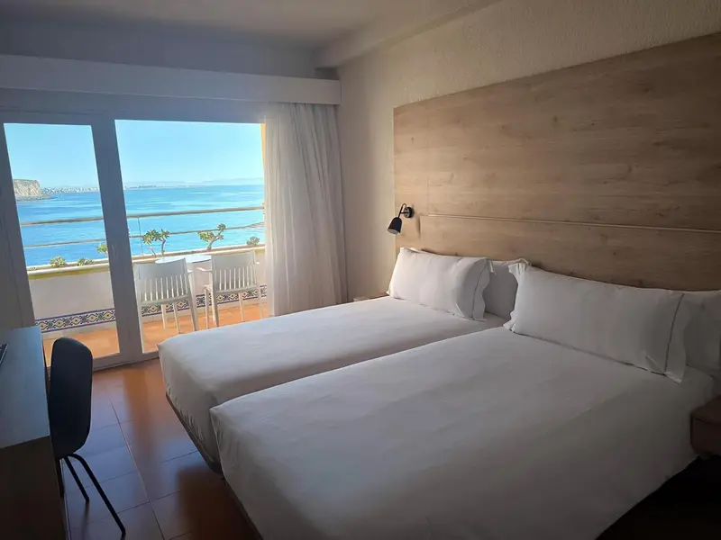 Une chambre lumineuse avec un grand lit donnant sur la mer.