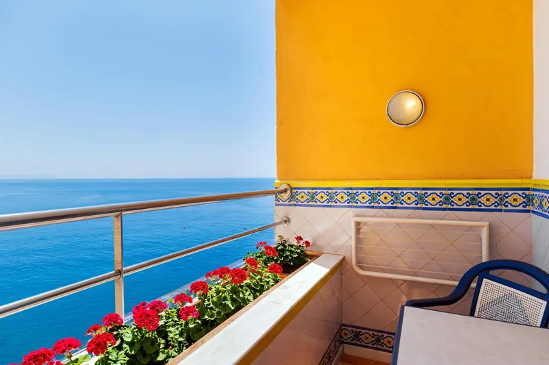 Balcon fleuri donnant sur la mer bleue.