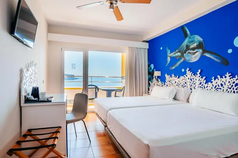 Chambre lumineuse avec vue sur la mer et décoration marine.
