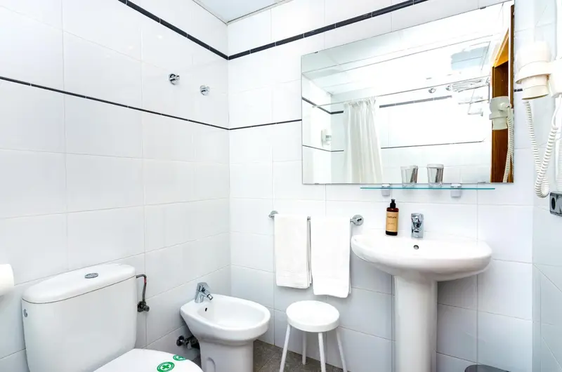 Une salle de bain claire avec des carreaux blancs et un lavabo.