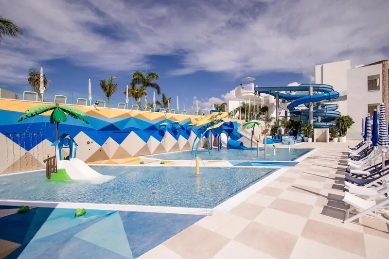 Espace aquatique avec toboggans et chaises longues près d'une piscine.