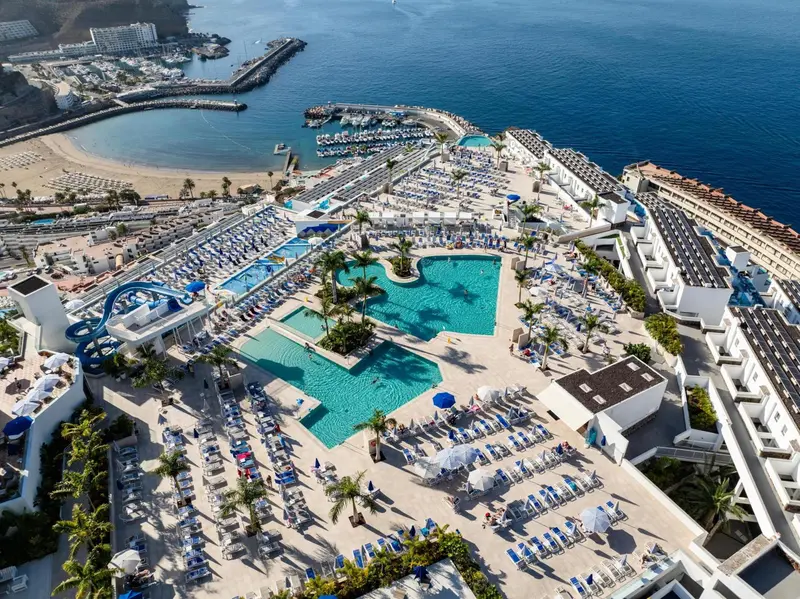 Vue aérienne d'un complexe hôtelier avec piscines et transats.