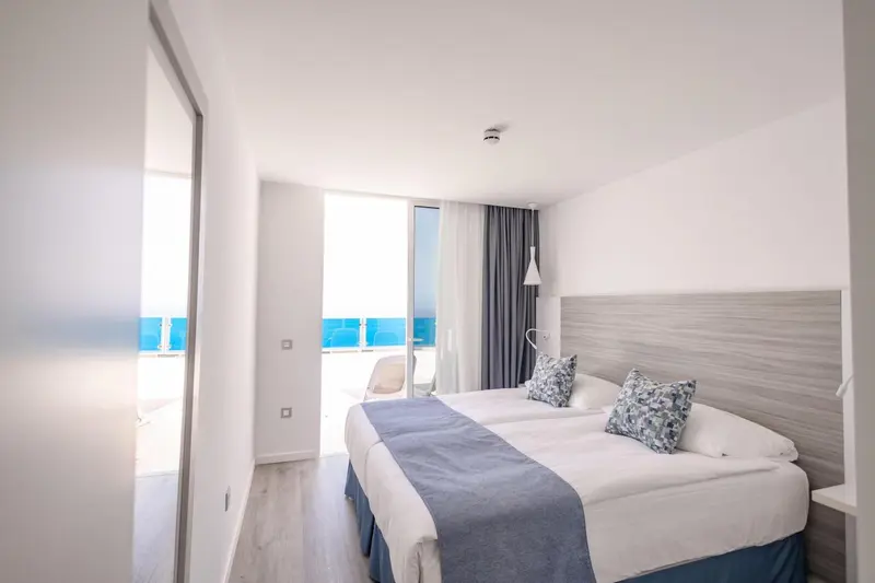 Une chambre lumineuse avec un lit double et un accès à une terrasse.