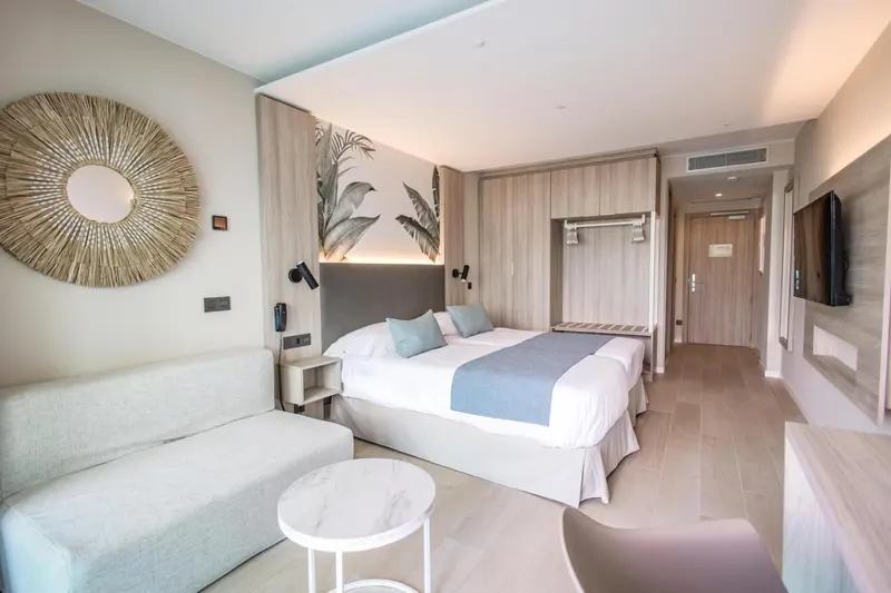 Une chambre lumineuse avec un grand lit et un coin salon.