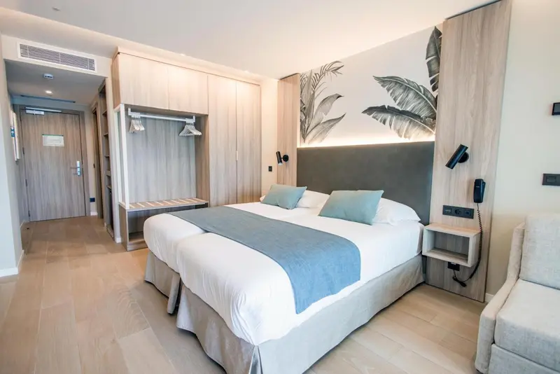 Chambre lumineuse avec un grand lit et une décoration moderne.