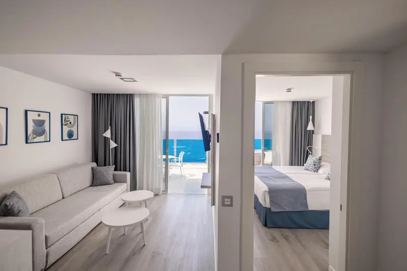 Espace de vie lumineux avec canapé et vue sur la mer depuis une baie vitrée.