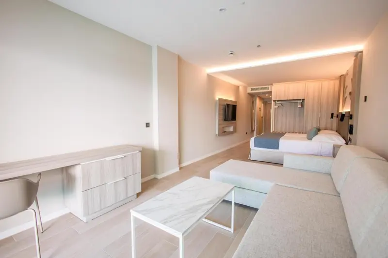 Une chambre lumineuse avec un coin salon et un lit double.