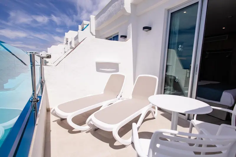 Deux chaises longues blanches invitent à la détente sur une terrasse ensoleillée.