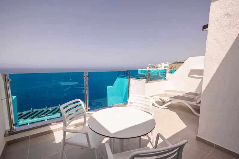 Terrasse avec mobilier blanc donnant sur la mer.