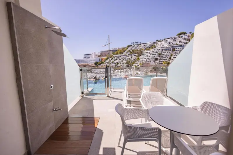 Espace extérieur aménagé avec douche et mobilier de jardin.