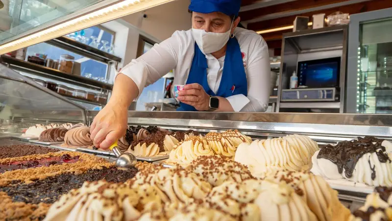 Un vendeur prépare des glaces artisanales derrière un comptoir vitré.
