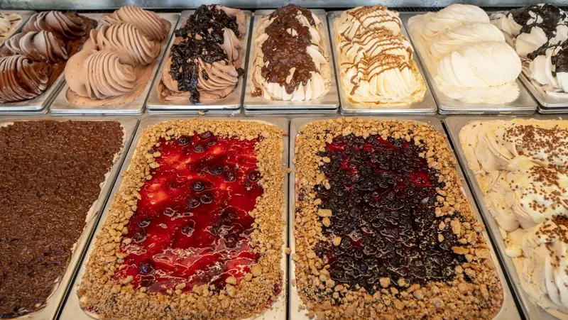 Présentation de différentes sortes de glaces artisanales dans des bacs réfrigérés.