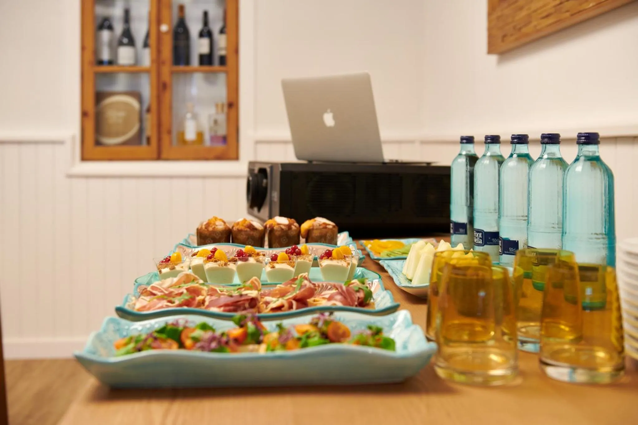 Une table garnie de plats variés et de boissons fraîches est présentée en intérieur.
