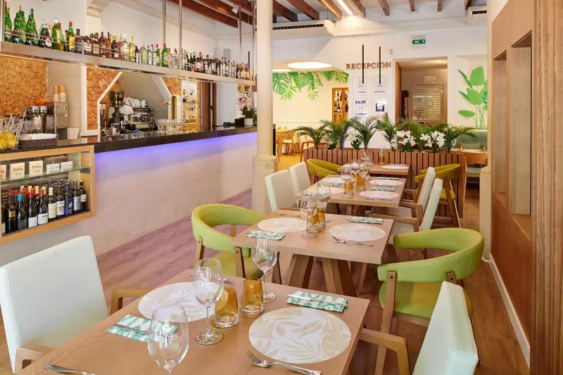Une salle lumineuse avec des tables dressées pour le repas et un comptoir de boissons.