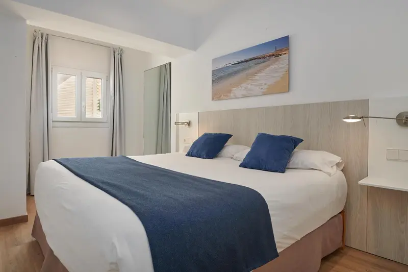 Une chambre lumineuse avec un grand lit et une décoration sobre.
