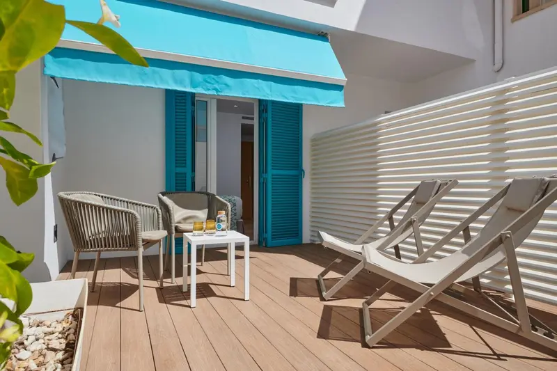 Terrasse aménagée avec mobilier de jardin et store bleu.