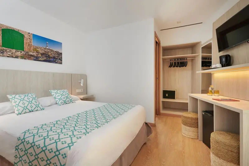 Chambre lumineuse avec un lit double et un espace bureau.