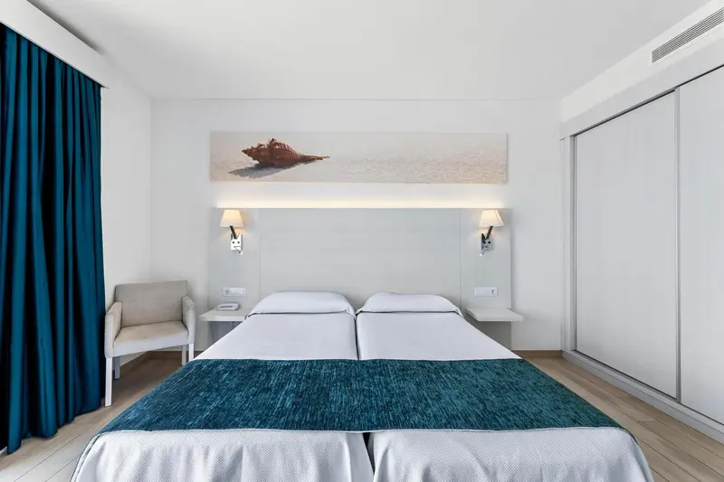 Chambre lumineuse avec un grand lit et une décoration sobre.